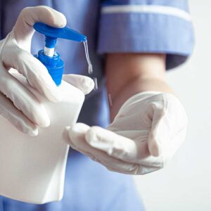 Nurse with gloves putting on hand sanitizer
