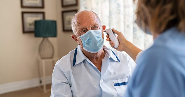 Nurse checking patient's temperature during COVID